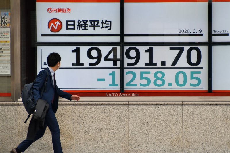 Office worker walk past in front of electronic stock board display in Tokyo, Japan on Monday, March 9, 2020, when the Nikkei average closing price dropped below 20,000 Yen line for the first time in 14 months. The yen fell to a 37-year low against the U.S. dollar on Wednesday. File Photo by Keizo Mori/UPI